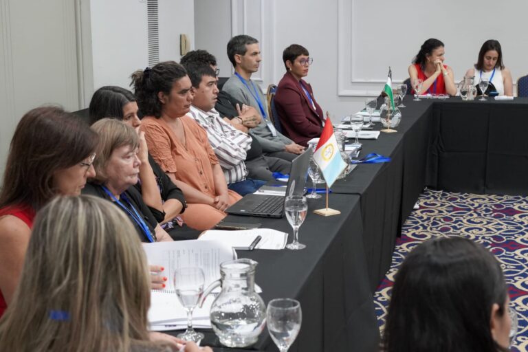 La secretaria ejecutiva del órgano de revisión de salud mental junto a otras personas sentadas en mesas, asistiendo a las Jornadas sobre salud mental.