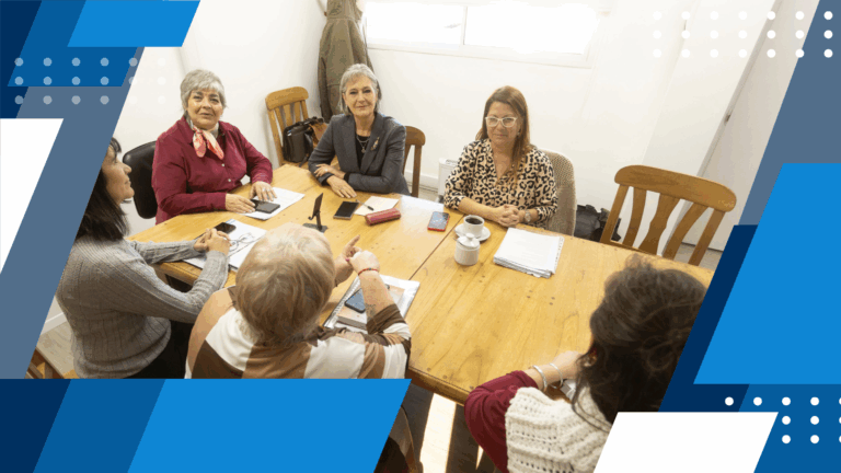 La defensora del pueblo de rio negro, junto a la ministra de educación, Patricia Campos, y otras personas conversando en una oficina alrededor de una mesa.