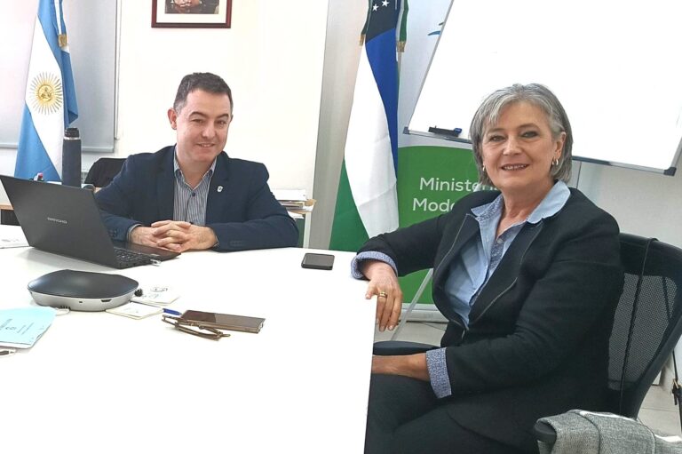 Adriana Santagati con el ministro de Modernización, Milton Dumrauf posan para la fotografia. Estan en una oficina se pueden ver las banderas de Argentina y Rio Negro de fondo.