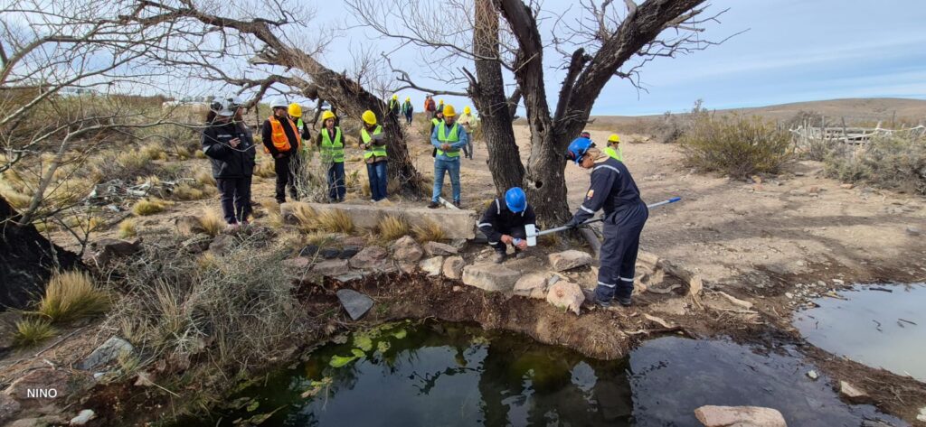 Personas con vestimenta de trabajo tomando muestra de agua de estanque