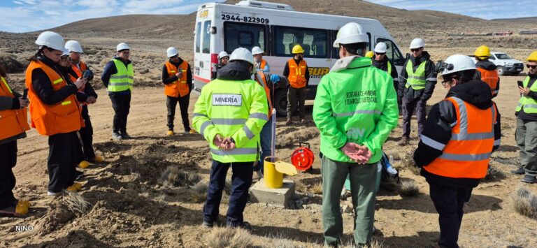 Personas con vestimenta de trabajo de tono vibrante junto a vehículos en un muestreo de agua en campo.
