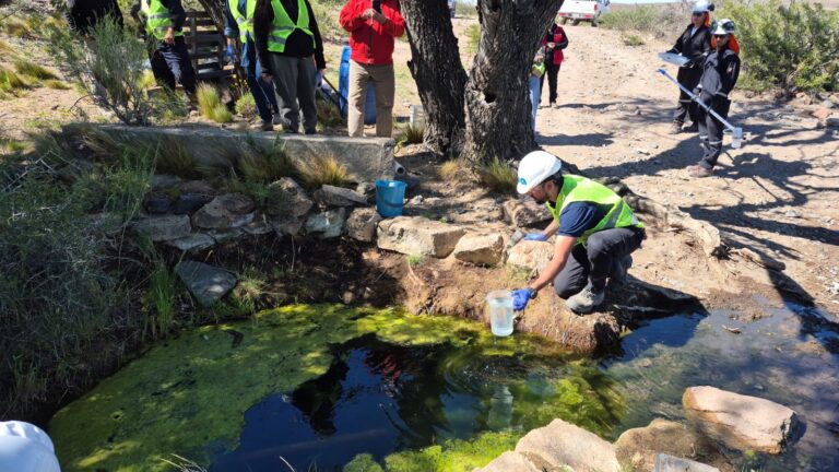Personas trabjaando, realizando muestreo de agua en estanque