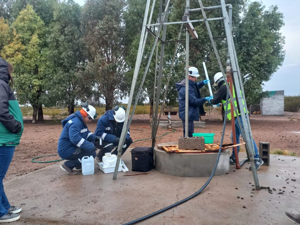 En la imagen se observan personas tomando la muestra de agua correspondiente al primer poso.